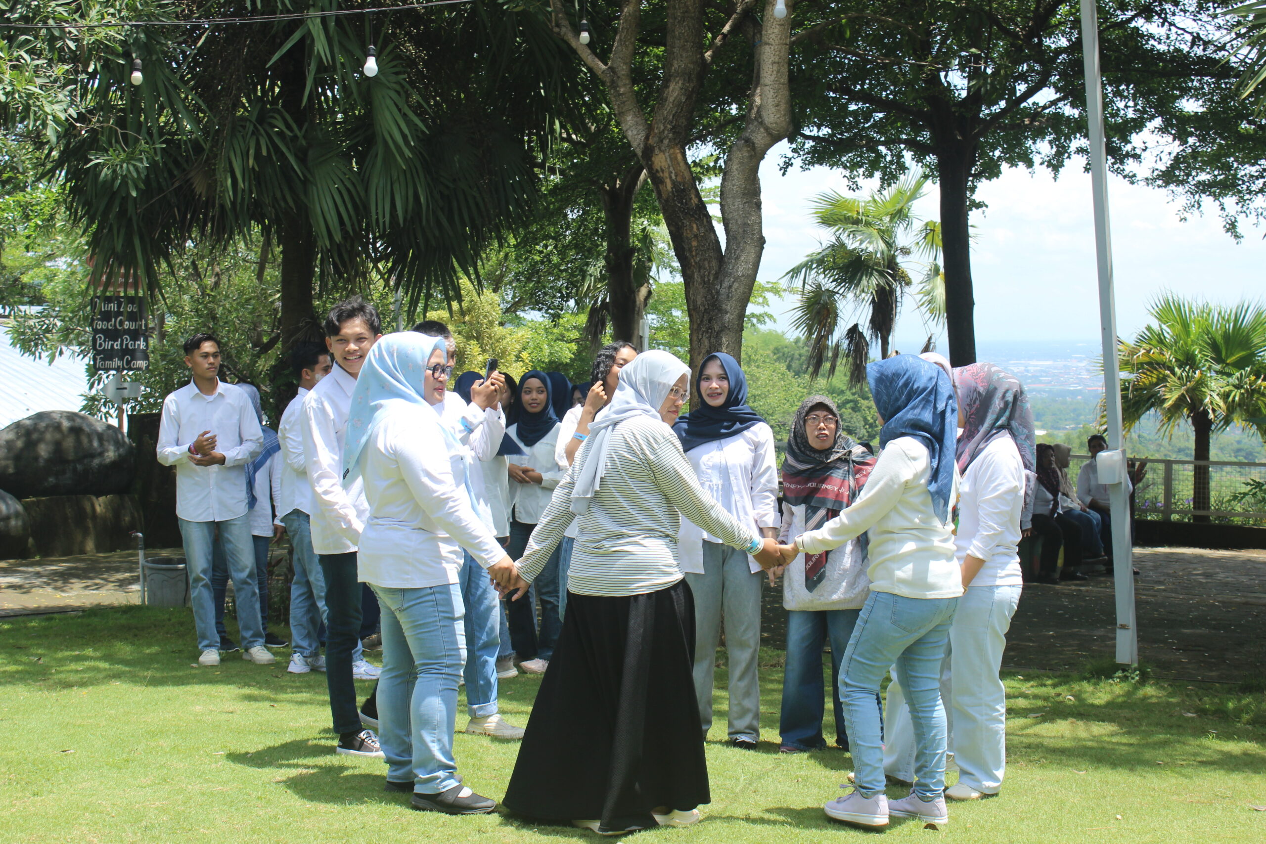 Peserta outbound membentuk lingkaran saat permainan kerja sama tim di lapangan hijau