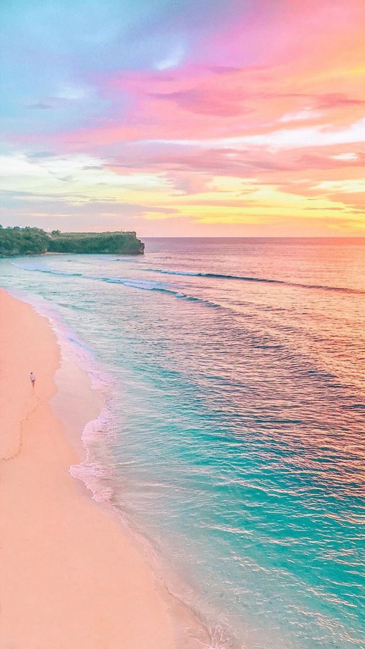 Pemandangan laut jernih bergradasi biru dan hijau di Pantai Tiga Warna dengan pasir putih dan perbukitan hijau di sekitarnya.